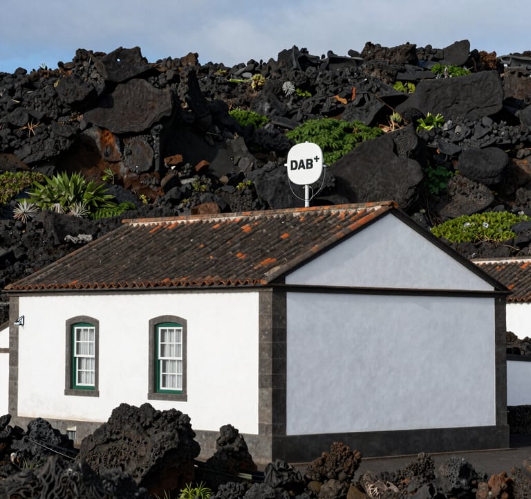 A traditional white-walled Atlantic island building with a discrete modern DAB+ antenna on its roof, surrounded by volcanic rocks and greenery in the Azores, European Atlantic / Insular.