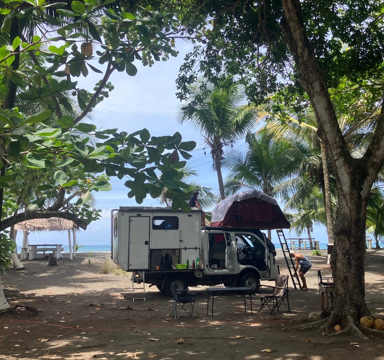 RV parked up against blue skies on the carribean coast at camping babsita in costa rica