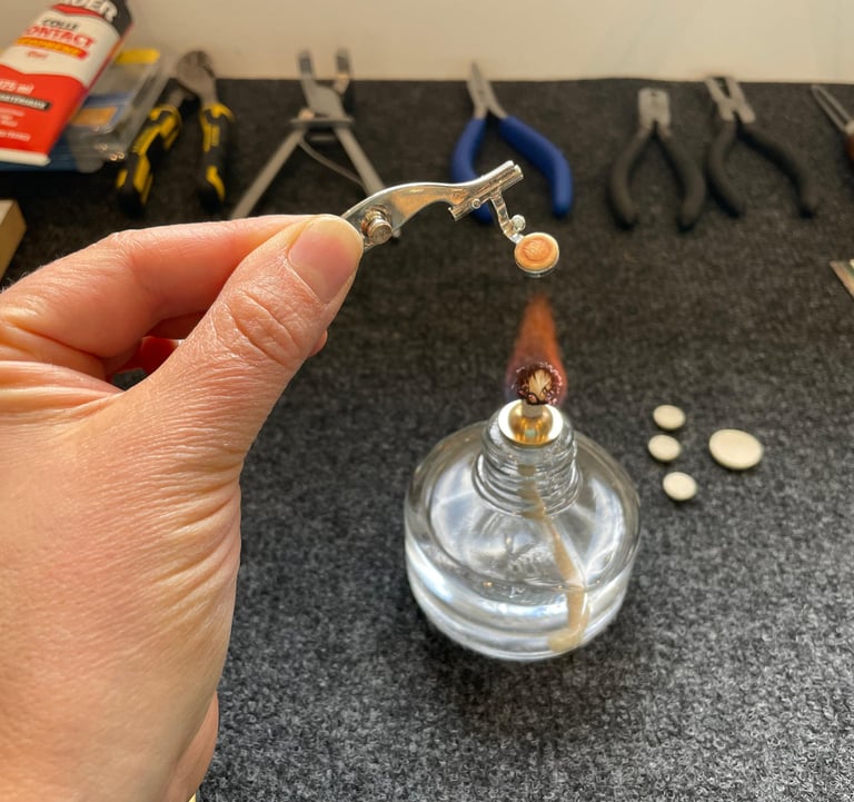 gros plan sur une main chauffant un piston de flûte traversière pour le réparer