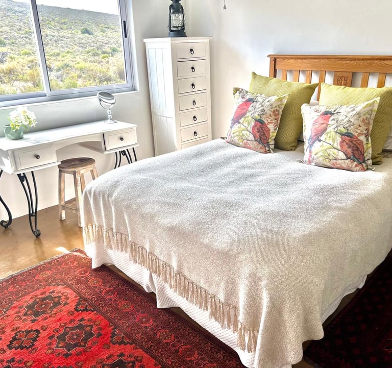  Reubens Choice bedroom decor featuring a wooden bed and a red Persian rug with a window view.