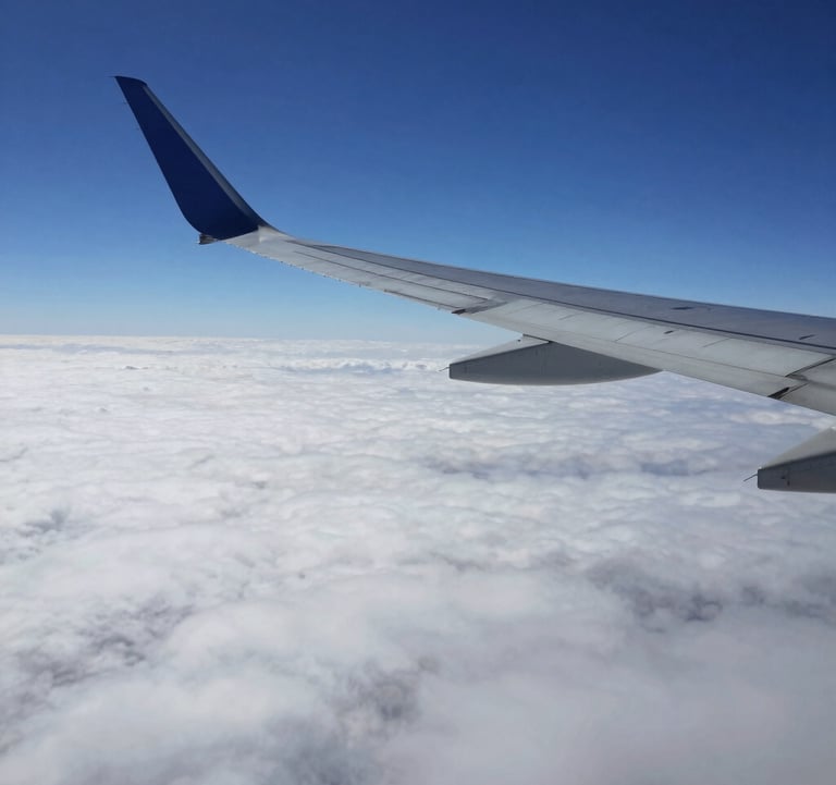 A wide shot of a modern airplane wing cutting through a sea of white clouds against a deep dark blue sky. Professional aerial photography, clean and inspiring a sense of freedom and ease.