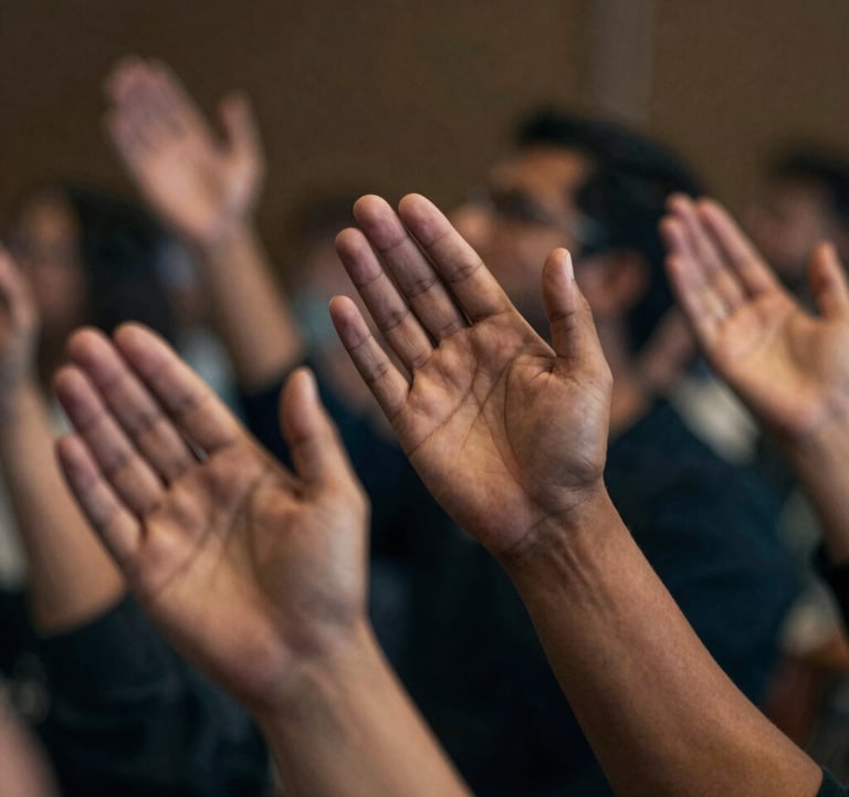 A close-up, spiritually profound image of hands reaching upward during a service. The lighting is cinematic and dramatic, using a palette of #0D131C and #D8B863. The focus is sharp on the expression of faith.