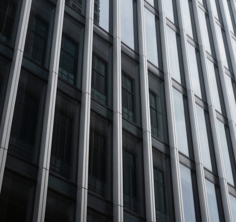 A minimalist, low-angle shot of a modern architectural facade in a North American city, featuring sharp silver geometric lines against a dark charcoal glass exterior, symbolizing structured business growth.