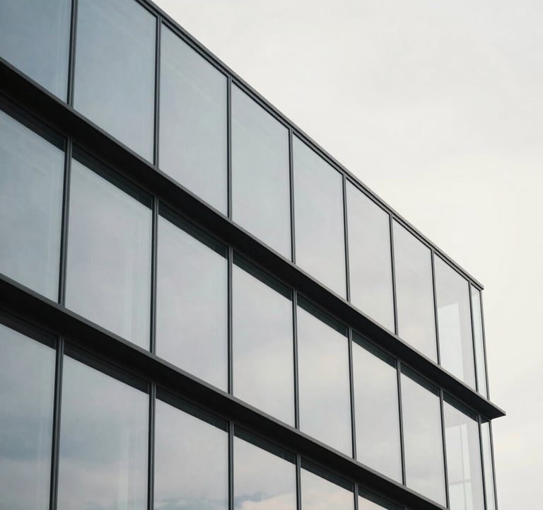 A minimalist architectural detail of a glass and steel building reflecting a cool off-white sky. The composition is geometric and clean, symbolizing structure, clarity, and precision.