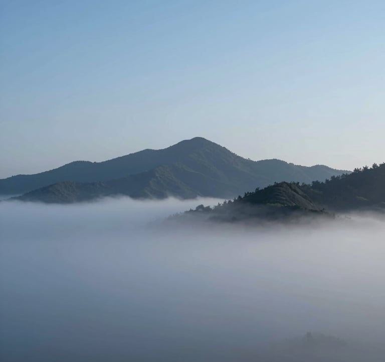 Breathtaking landscape photo of mist-covered mountains at dawn. Minimalist composition with cold blue sky #4A7B8E and sharp charcoal peaks. High-end editorial style.
