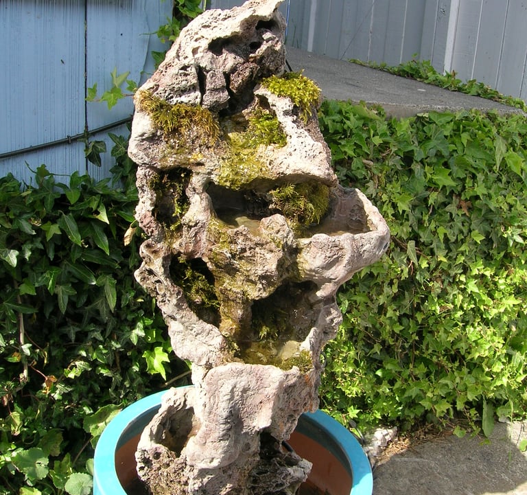 3.5-foot tall handmade stone column by Phil Mikkelson, moss-covered and designed as an outdoor water