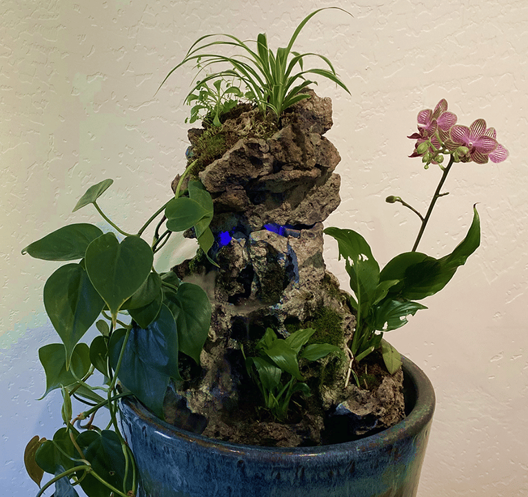 Indoor waterfall sculpture with sculpted stone, orchid, philodendron, and spider plant