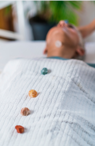 Une personne allongée, recevant un soin de lithothérapie, entourée de cristaux et pierres précieuses