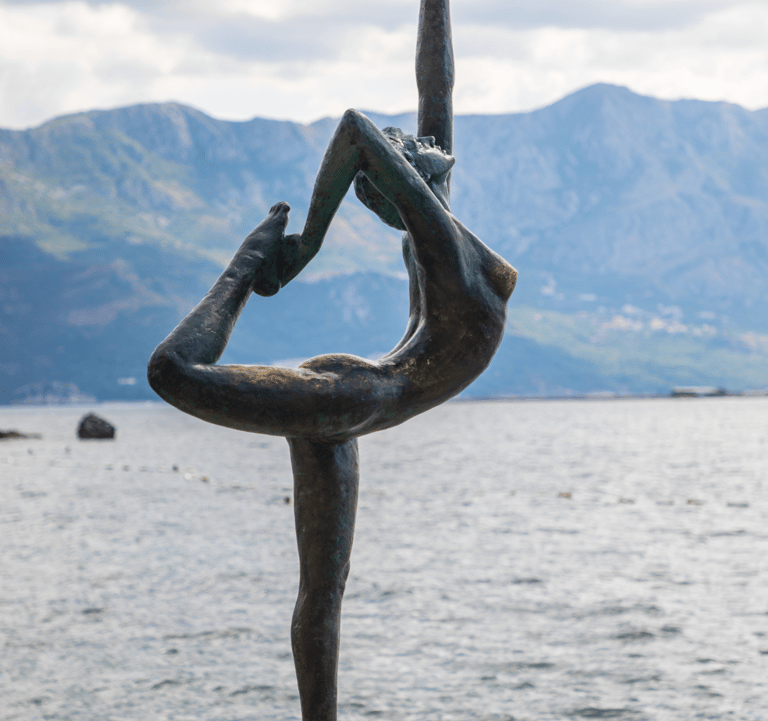 a statue of a woman doing yoga on a rock