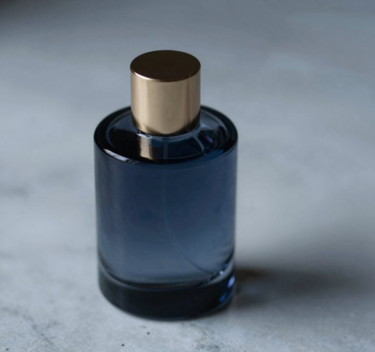 A minimalist, dark glass perfume bottle resting on a cold marble surface. Soft gold highlights (#B08D5B) on the cap, shadows in deep blue (#0C1E38), atmospheric lighting.