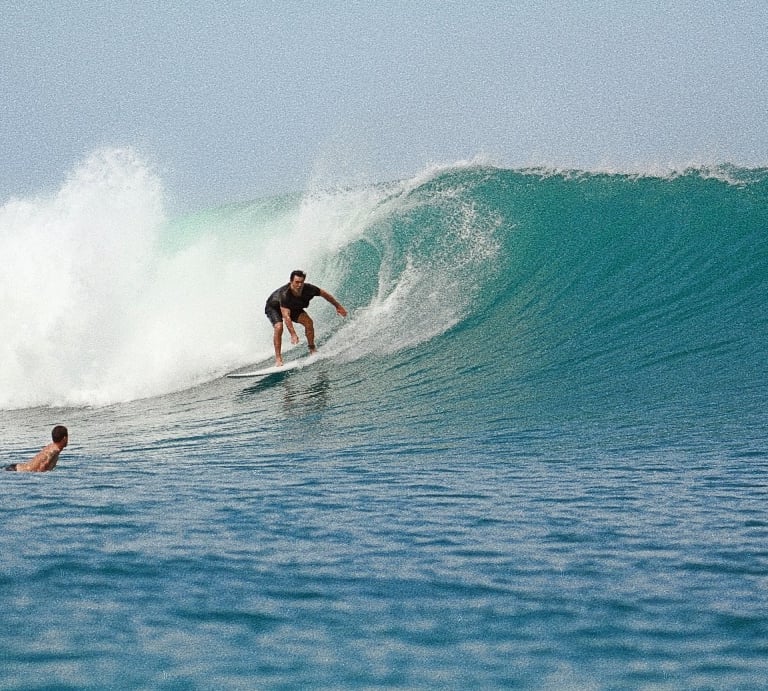 a man riding a wave in the ocean with his friend 