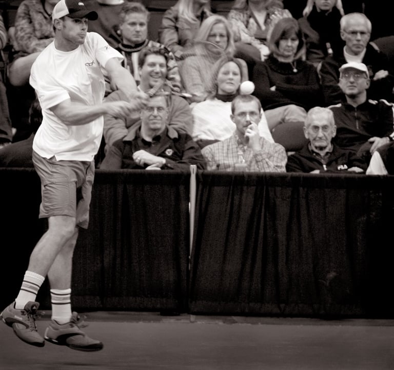 a man playing tennis in a crowd of people