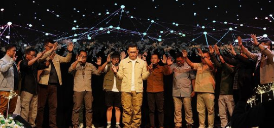 a man standing on a stage with his hands up in the air