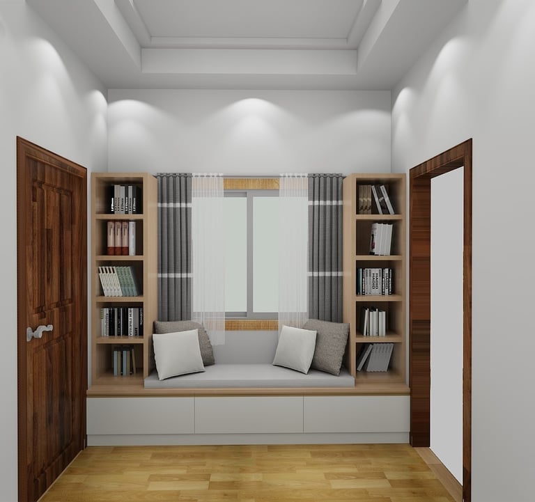 Modern reading nook with window seat, built-in bookshelves, and gray pillows in a white room.