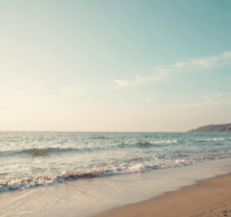 A tranquil photo of a hidden beach at sunset, with soft waves lapping the shore. The sky is a mix of #A8C9CF and warm off-white tones, evoking a sense of peaceful wanderlust and discovery.