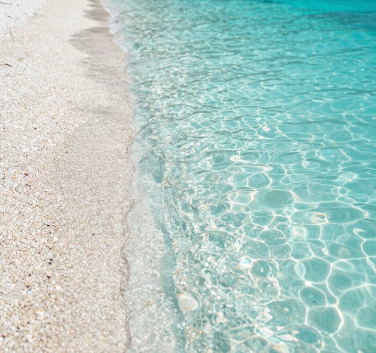 A high-quality photo of a hidden beach with turquoise water and smooth pebbles. The lighting is bright and natural. The colors include #A8C9CF and #F7F9FA. Authentic travel vibe.