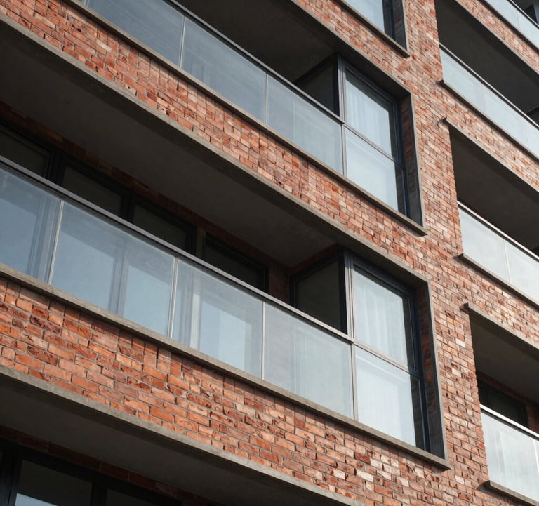 A close-up architectural detail shot of a premium facade with high-quality brick and glass finish, emphasizing the construction quality and modern design of a South Asian development.