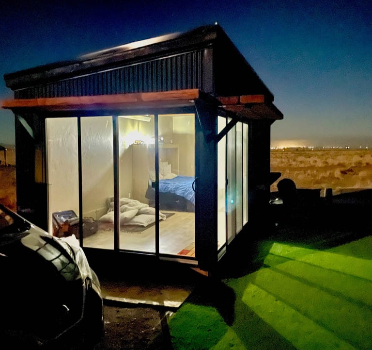 a small cabin with a bed and a car parked in front of it