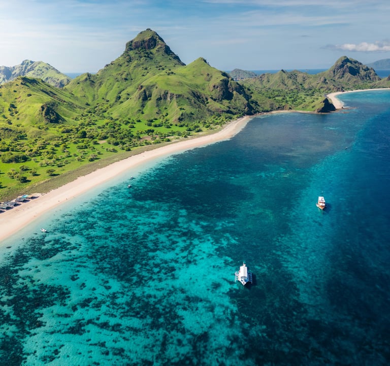 Aerial view of a Komodo Island in Indonesia, showing turquoise waters, rugged coastline, and lush gr