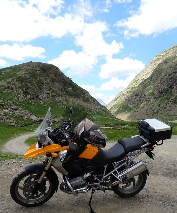 a motorcycle parked on a dirt road near a mountain