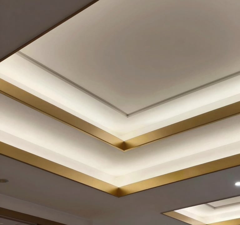 Detail of a custom false ceiling with layered geometric patterns, soft white recessed lighting, and a thin metallic gold border.