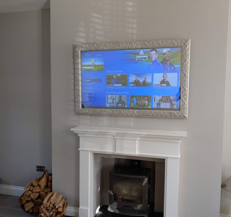 Bespoke Samsung TV installation above a fireplace featuring a custom-made frame and mirror glass