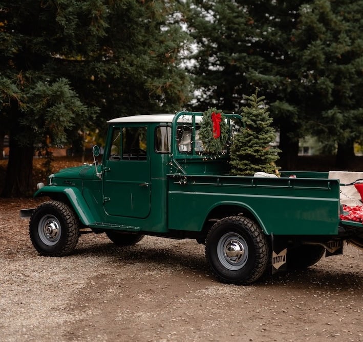A photo of a green 1967 Toyota Land Cruiser pickup in a wooded setting.