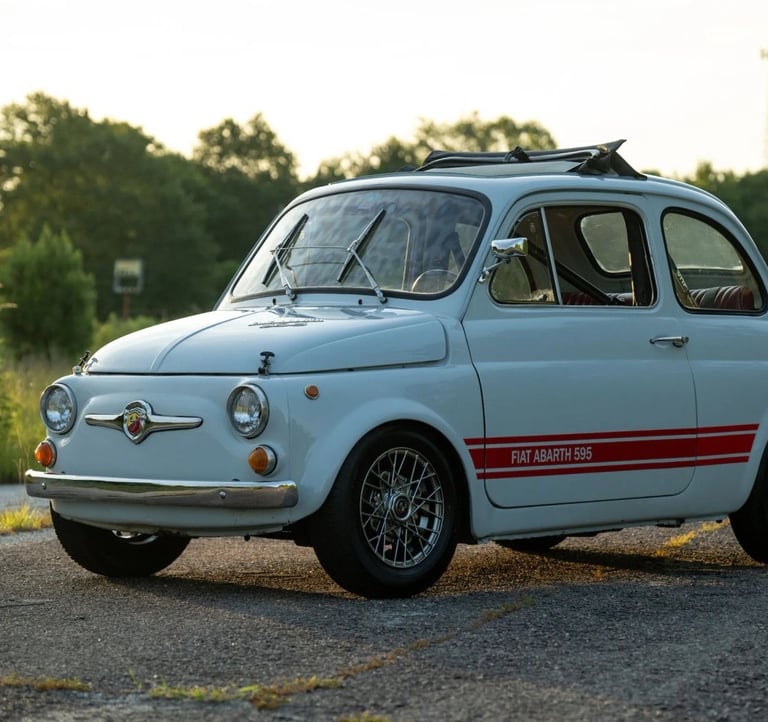 A photo of a blue grey 1974 Fiat 595 SS Abarth in a wooded setting at dusk.