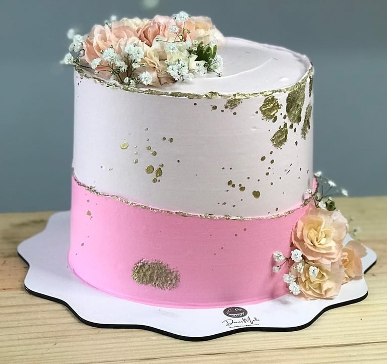 Bolo decorado em camadas com rosas, flores brancas e detalhes dourados, perfeito para festas e comem