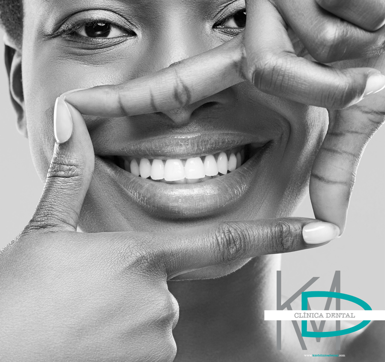 Mujer sonriente mostrando dientes blancos en fotografía en blanco y negro, con logo de KMD Clíni