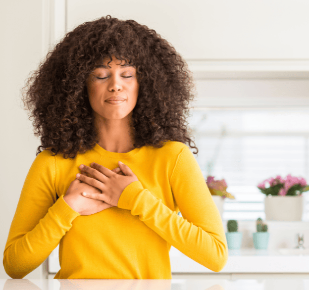 a lovely young black woman expressing gratitude with her hands on her heart