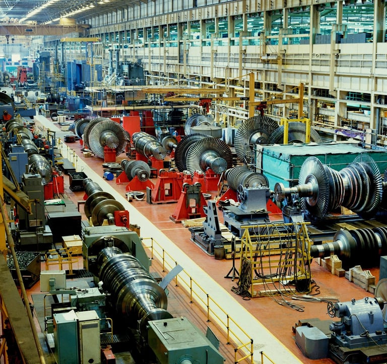 Industrial turbine manufacturing facility with heavy machinery and rotating components on a large assembly floor.