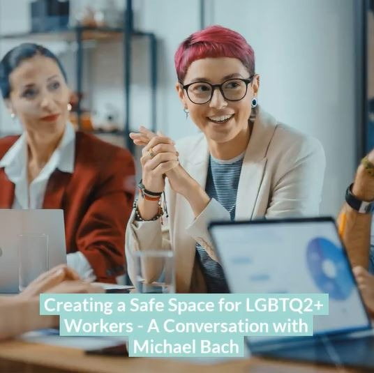 Image of a woman with red hair seated at a meeting, next to another woman, laptops open