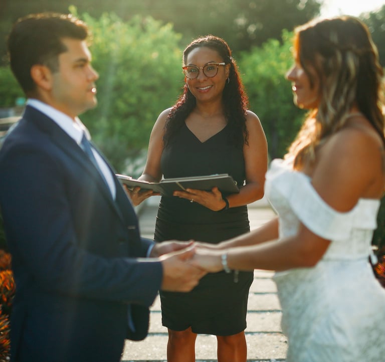 A wedding officiant performing a ceremony at Bonnet Springs, for a bride and groom holding hands.