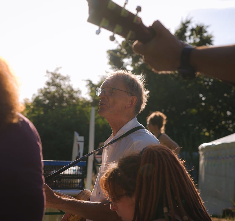 Menschen musizieren zusammen im Sonnenuntergang vor einer Jurte.