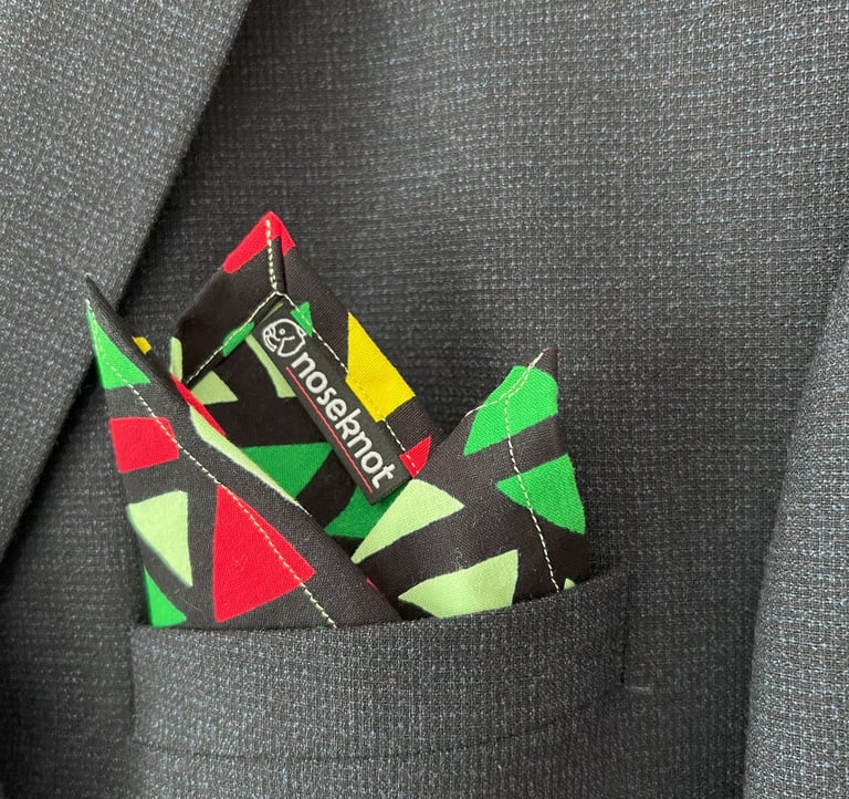 A Noseknot handkerchief showing the Noseknot logo in a suit pocket