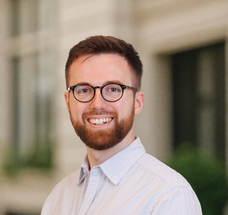 a man with a beard and glasses on a city street