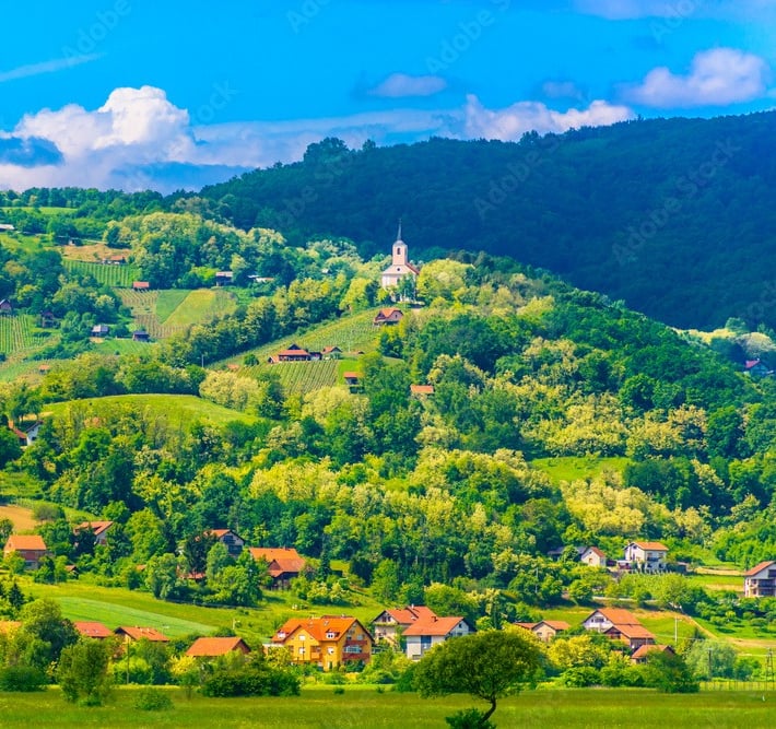Prekrasan pogled na krajolik Zagorja. U brdima se vide malene kućice i crkva.