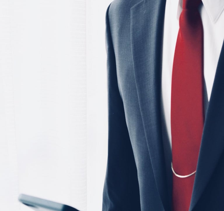 Um homem de paletó e gravata segurando um celular nas mãos