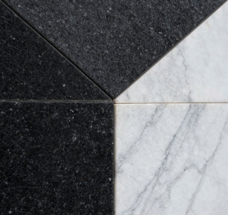Close-up architectural detail of textured black basalt stone and sleek white marble. The composition is geometric and abstract, emphasizing light and shadow. Soft, diffused lighting. North American / International editorial style.