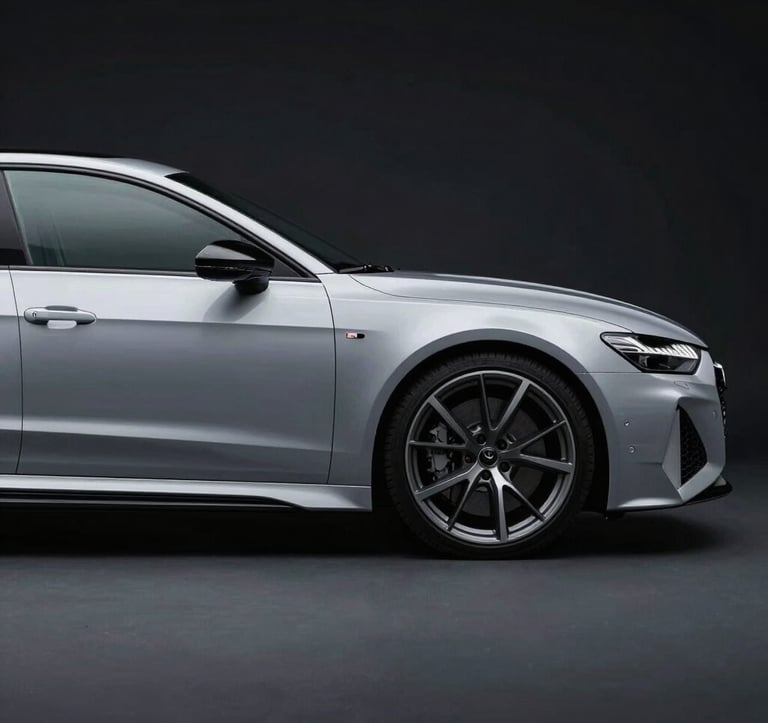 A side profile photograph of a silver Audi RS7 under cool, studio lighting. The car is positioned against a Deep Obsidian Black backdrop, emphasizing its sharp aerodynamic lines and the glint of Cool Slate Grey alloy wheels.