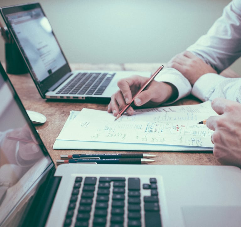 A person working on a paper, presenting to another person.