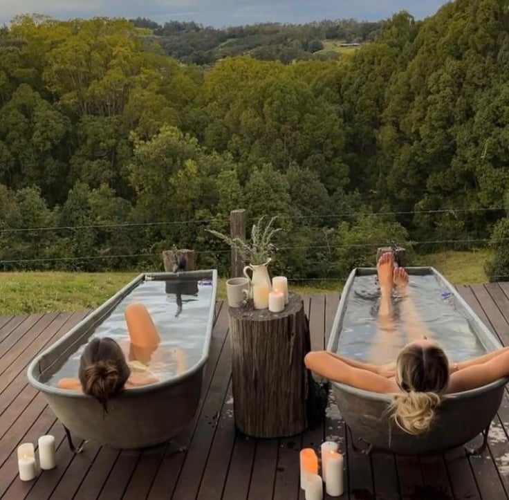 two ladies relaxation in an outdoor bath in nature at a wellness retreat by Luxe Wellness Spaces