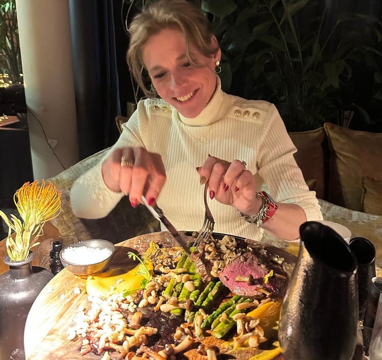 een lachende vrouw die een stuk vlees snijdt