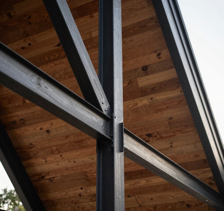 Close-up detail of the modern A-frame structure showing the intersection of charcoal black steel beams and warm wooden cladding. Sophisticated architectural textures under soft sunlight.