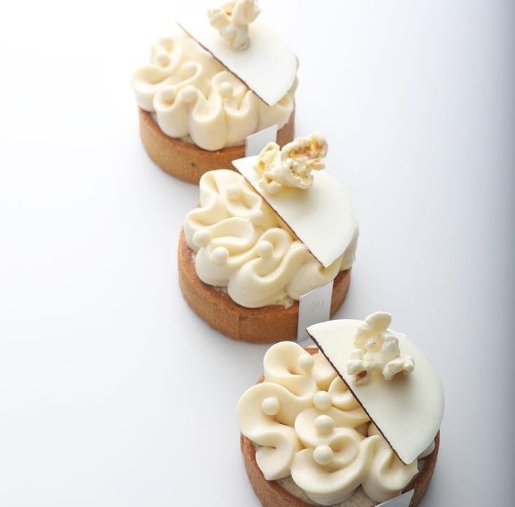 a row of three cakes with white frosting