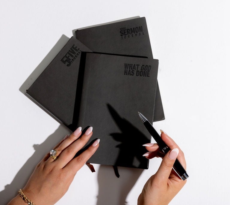 a woman's hands holding a notebook with a pen
