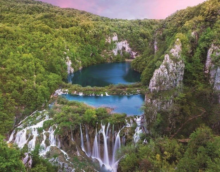 Wooden walkways leading through turquoise lakes and waterfalls in Plitvice Lakes National Park.