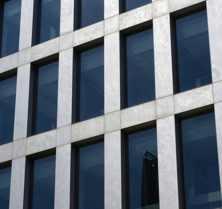 Close-up detail of a modern commercial office building in Bangalore. The facade uses Soft Silver panels and Dark Navy Blue tinted glass. The style is professional and elegant, captured in bright daylight.