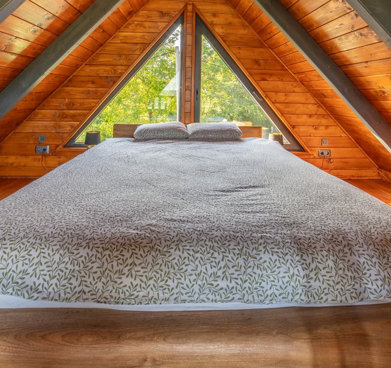 a bed in a loft apartment with a view of the trees